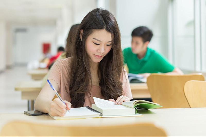 Cô gái ngồi viết vào sổ ghi chép.